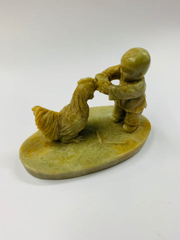 Carved stoneware child feeding a rooster