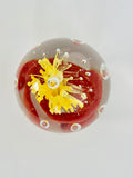 Clear Paperweight with a Swirl of Red with a Yellow Flower in the center