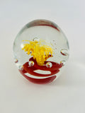 Clear Paperweight with a Swirl of Red with a Yellow Flower in the center