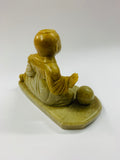 Stoneware carved figure sitting with a ball