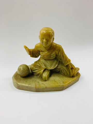 Stoneware carved figure sitting with a ball